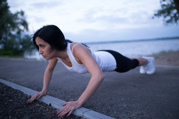 Sporty woman push up at river in twilight