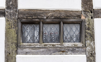 Traditional Tudor style window frame, with wooden beams surrounding the glass pane