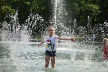 Enjoy fountain, young girl bathes in a city fountain
