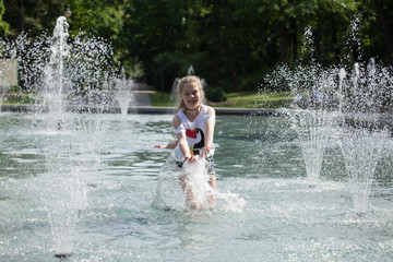 Enjoy fountain, young girl bathes in a city fountain
