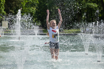 Enjoy fountain, young girl bathes in a city fountain
