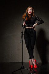 Portrait of beautiful singer in red heels and black clothes