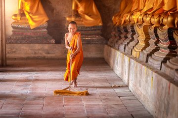 Little novices cleaning with mop the floor at Ayutthaya Historical Park in Thailand