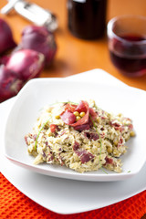 Risotto con bresaola e piselli nel piatto di ceramica bianca sulla tavola apparecchiata