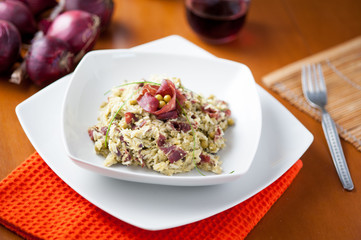Risotto con bresaola e piselli nel piatto di ceramica bianca sulla tavola apparecchiata