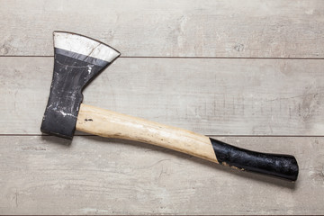 Wooden handle axe lying on wooden table. Top view.