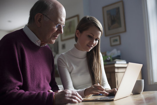 Granddaughter Helping Grandfather To Use Laptop Computer