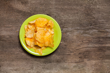 Potato chips in white plate on wood table .Top view.