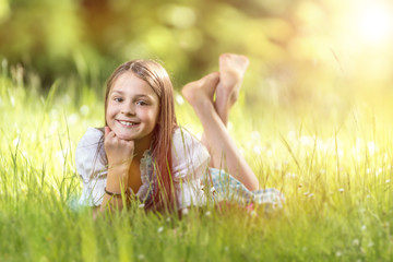 Naklejka na ściany i meble Smiling Girl lying in the Gras in Summer