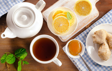 Teapot and cup of tea with lemon, ginger and mint