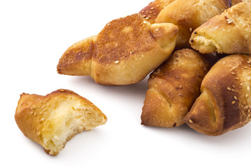 Fresh Serbian pastry rolls with cheese and sesame, kifla kiflice, one bitten, isolated on white background
