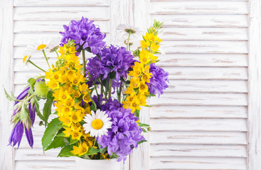 Bouquet of wild flowers on white wooden background