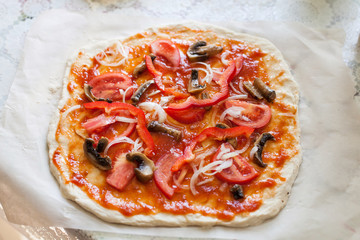 Raw homemade pizza with tomatoes, olives, sweet pepper