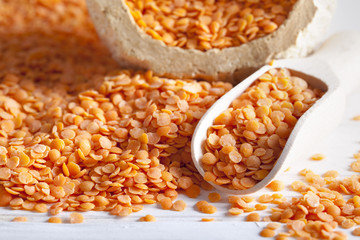 Red lentils on white wood background