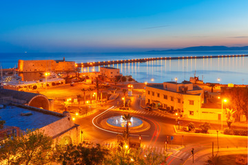 Aerial view of old harbour of Heraklion with Venetian Koules Fortress and marina during blue hour after sunset, Crete, Greece.