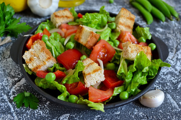 Vegetable salad with romano, tomatoes, peas and croutons on a co