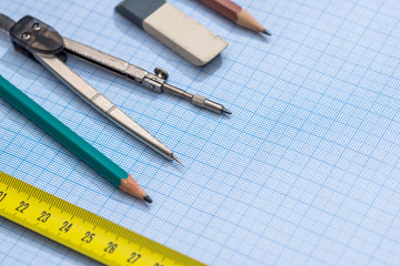 pencil, compass and rulers on graph paper background
