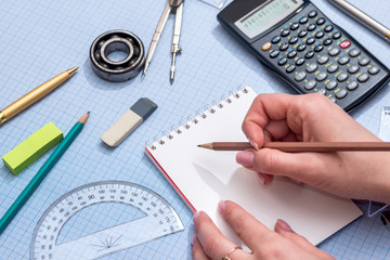 blank notepad, rolls of engineering drawings with tools on graph background