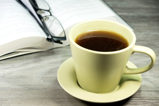 Kaffeetasse, Lesebrille und ein Buch