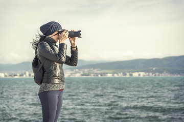 Girl photographer takes photos or videos near the sea.