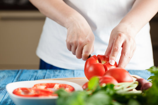 Closeup Of Young Woman In Kitchen Cutting Vegetables