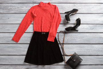 Red top and black skirt. Dark heel shoes and handbag. Spring sale in brand shop. Attractive female clothes and accessory.