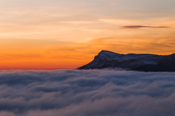 Beautiful sunset on the hill above clouds