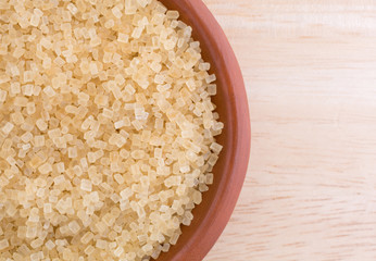 Top close view of Turbinado sugar in bowl on a wood table top.