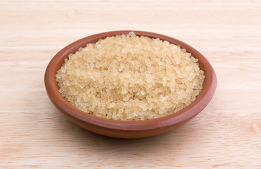 Turbinado sugar in a small bowl on a wood table top.