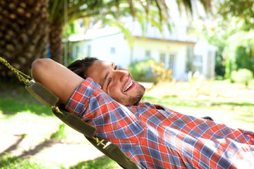 Attractive young man lying in hammock and smiling