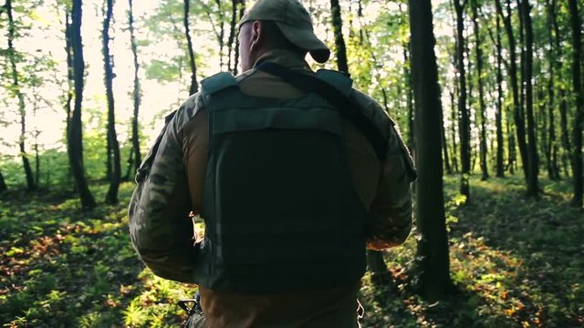 Young military goes in the forest and looks back
