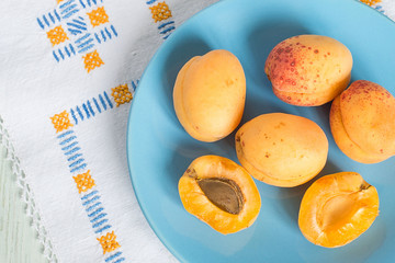 Apricots.   Apricots on a blue plate on a napkin on a light wooden background.
