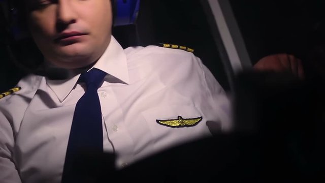 Concentrated male pilot checking flight indicators, making notes in documents