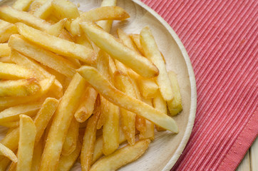 Close up, French fries sprinkled salt on wood plate
