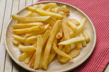 Close up, French fries sprinkled salt on wood plate