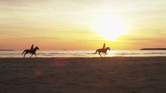 Silhouette of Two Riders on Horses at Beach in Sunset Light. Shot on RED Cinema Camera.