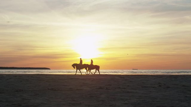 Silhouette of Two Riders on Horses at Beach in Sunset Light. Shot on RED Cinema Camera.