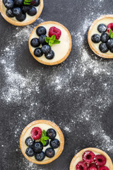 Delicious tartlets with raspberries and blueberries on slate background
