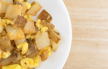 Top close view of a breakfast meal on a plate atop a wood table.