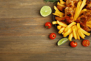 Baked chicken wings with French fries on wooden table