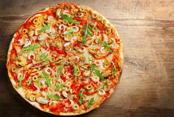 Pizza with seafood, red pepper and green olives on wooden table
