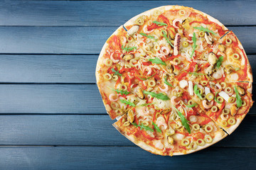 Pizza with seafood, red pepper and green olives on blue wooden table