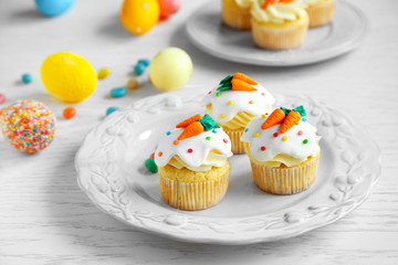 Plate with Easter cupcakes and eggs on wooden table