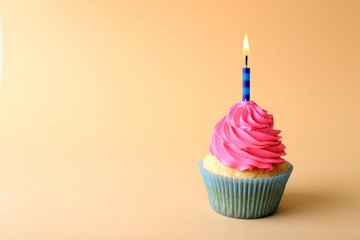 Birthday cupcake with candle on color background