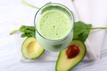 Delicious fresh avocado smoothie on white wooden background