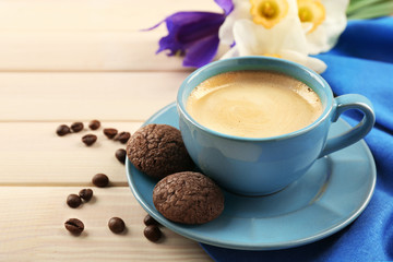 Cup of coffee with cookies and flowers on wooden table