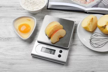 Badezimmer Foto Rückwand Making apple pie. Using digital kitchen scales on wooden table. Cooking apple cake concept © Africa Studio