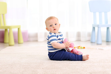 Adorable baby with pink bear on a floor