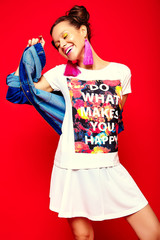portrait of cheerful fashion hipster girl in casual hipster  summer clothes jeans jacket on red...