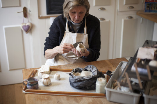 Mature Woman Sitting At Table Making Ceramic Pot
